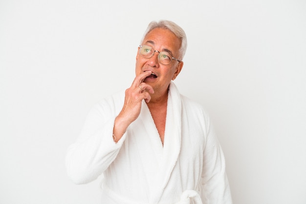 Senior american man wearing bathrobe isolated on white background relaxed thinking about something looking at a copy space.