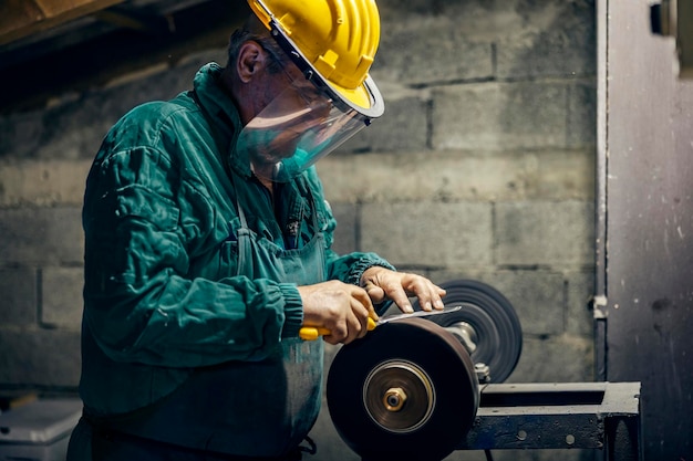 A senior artisan is sharpening blade on whetstone in his workshop