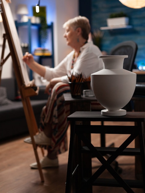 Senior artist using pencil and drawing vase design on canvas