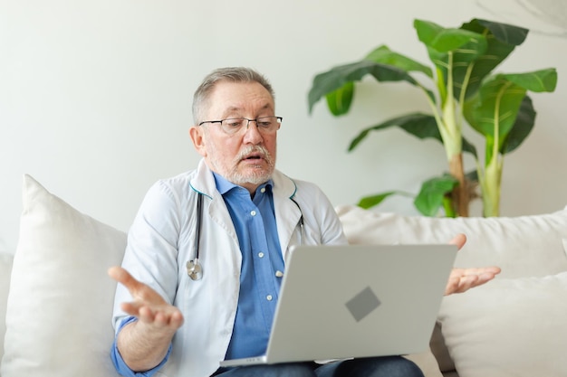 Senior arts met laptop praat op videogesprek heeft consultatie met patiënt professionele senior