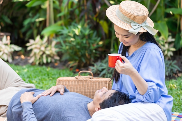 Senior Asian couple drinking coffee and picnic at garden.