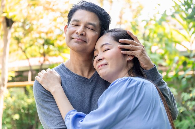 Le coppie asiatiche senior abbracciano insieme al giardino.