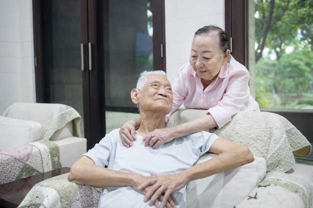 Senior Asian Couple Embracing Each Other on the Sofa