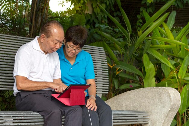 Foto coppie asiatiche senior che leggono insieme una compressa mobile