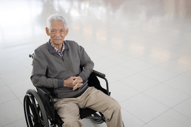 Foto ragazzo asiatico senior che si siede su una sedia a rotelle
