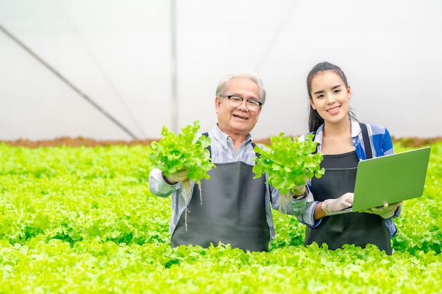 写真 農場で野菜の鮮度を示す年配のアジア人の男性と女性の農家