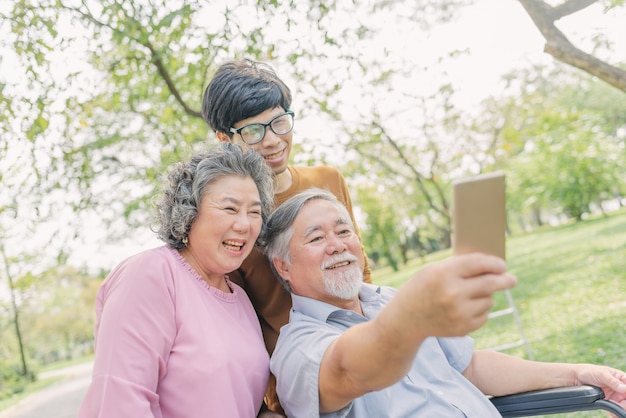 그의 가족과 함께 selfie 스마트 폰을 사용하여 수석 아시아 남자