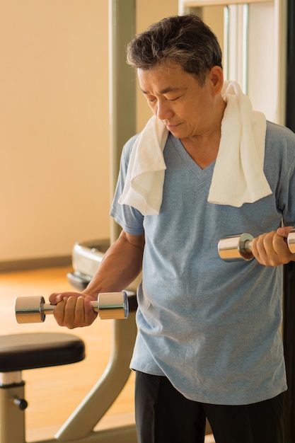 Senior uomo asiatico che risolve, allenamento con i pesi con manubri