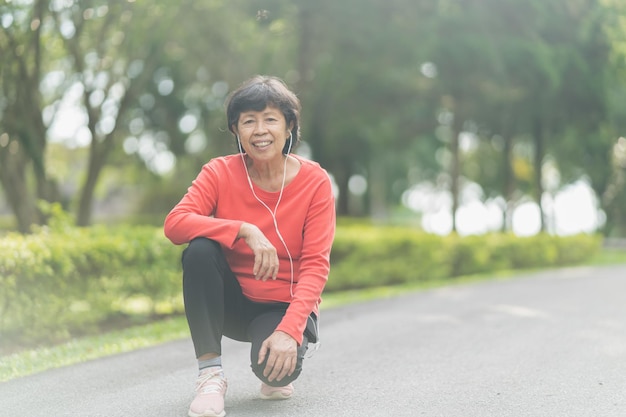 Senior asian woman body warming before exercising Old woman stretching before jogging in garden