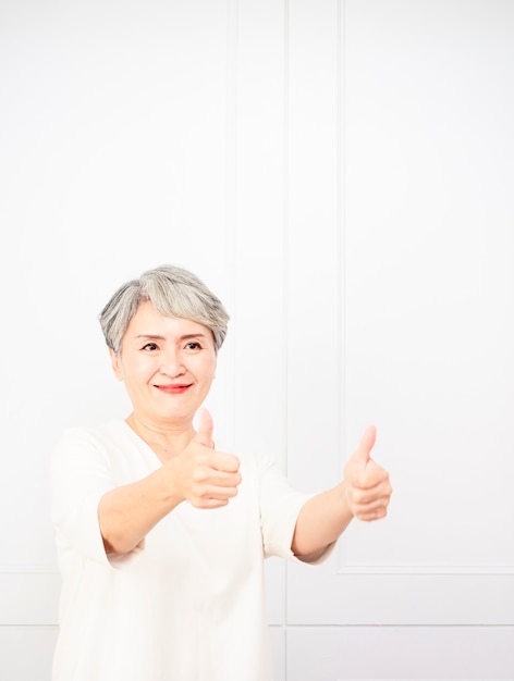 Senior asian woman holding her thumb up.