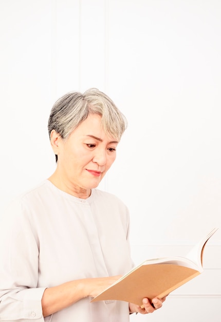 Senior asian woman holding and reading book.