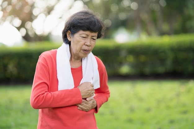 Senior asian woman suffer from exercise pain. Senior woman having heart attack after exercise at park. Health concept