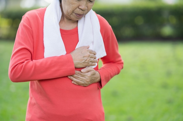 Senior asian woman suffer from exercise pain. Senior woman having heart attack after exercise at park. Health concept