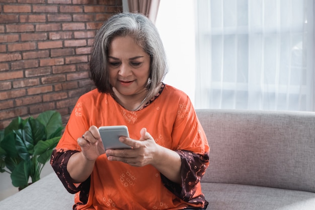 Donna asiatica senior che per mezzo del suo smart phone