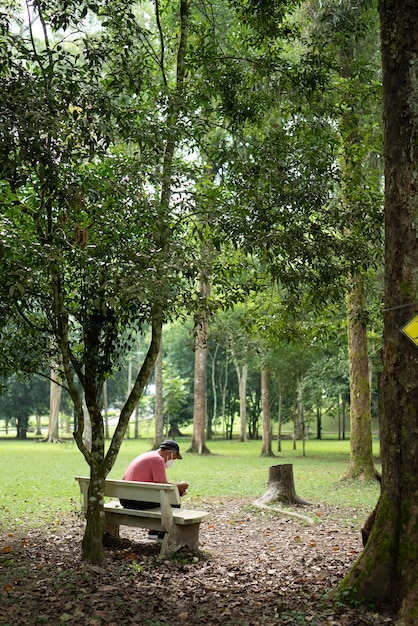 Senior aziatische man met een gezichtsmasker en zittend in een park