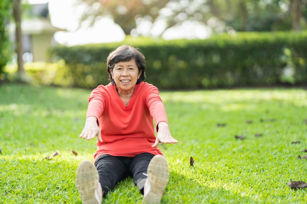 Senior aziatische vrouw lichaamsverwarming voor het sporten Oude vrouw die zich uitstrekt voordat ze in de tuin jogt