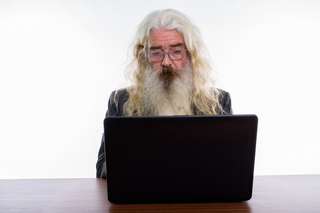 Senior Bearded Businessman Using Laptop On Wooden Table