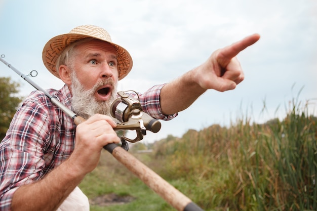 Senior bearded man fishing on a lake