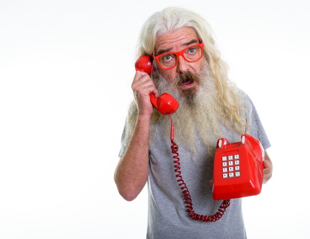 Photo senior bearded man looking shocked while talking on phone