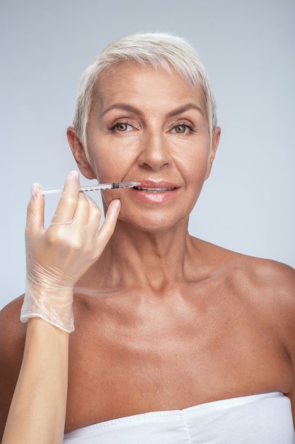 Senior beauty. Attractive blonde keeping smile on her face while visiting clinic