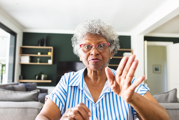 Senior biracial woman with gray hair gestures a stop sign with her hand on video call at home