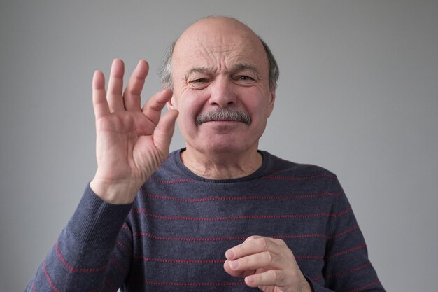 Senior blanke man gebaren met de hand met een klein bordje met vingers