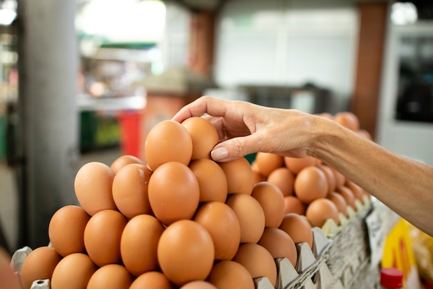 Senior blanke vrouw die kippeneieren koopt op de markt.