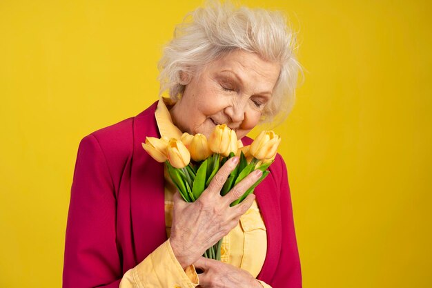 Senior blanke vrouw met gesloten ogen snuiven boeket gele tulpen