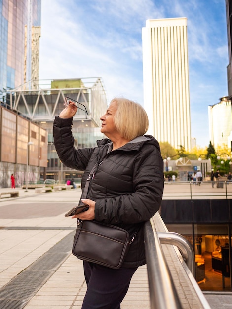 Photo senior blonde business woman looks at her glasses