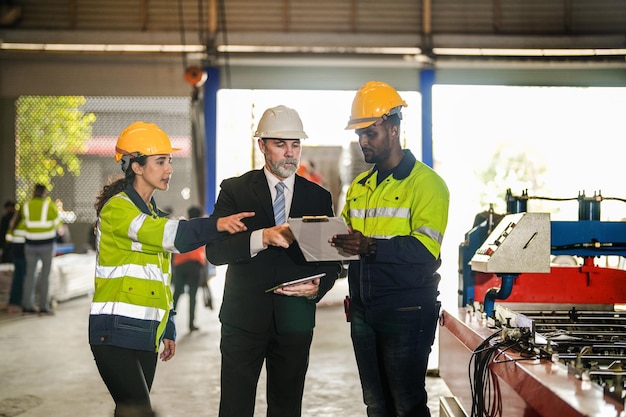 Senior boss manager talking staff engineer assistant woman and African manTeam engineering inspection check control heavy machine construction installation in industrial factory with boss manager