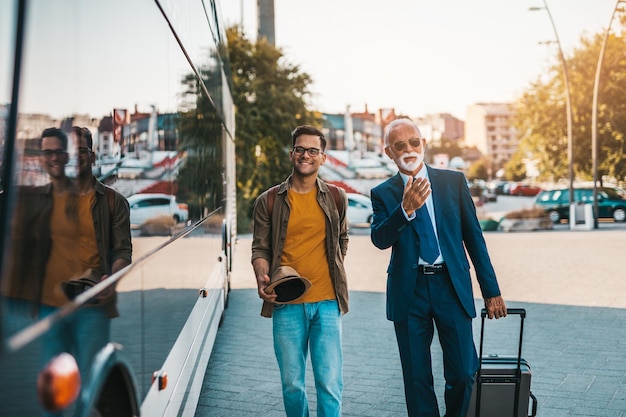 The senior bus driver accepts luggage from passenger.