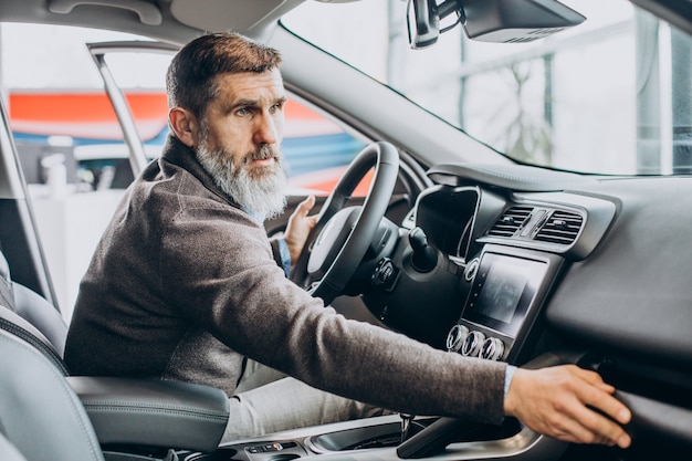 Uomo d'affari senior che sceglie un'auto nell'autosalone