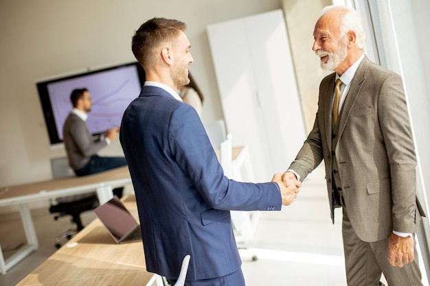 Senior business man handshaking with his young colleague