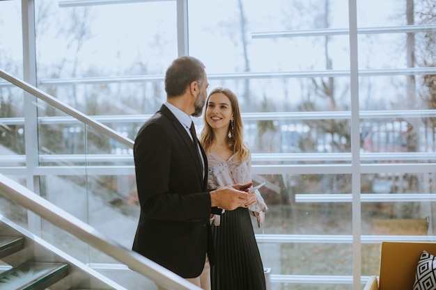 Senior business man and his young female colleague standing in office with digital tablet