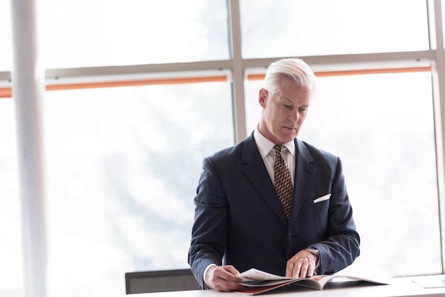 senior business man reading magazine at modern bright office