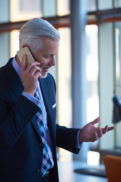 senior business man talk on mobile phone  at modern bright office interior