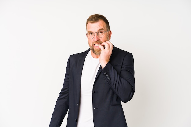 Senior business man on white wall biting fingernails, nervous and very anxious.