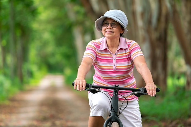 Senior donna d'affari giro femminile o mountain bike in bicicletta per un sano esercizio nel fine settimana estivo