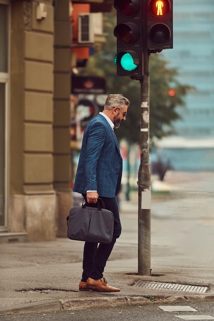 A senior businessman in a blue suit with a briefcase walking through the city.