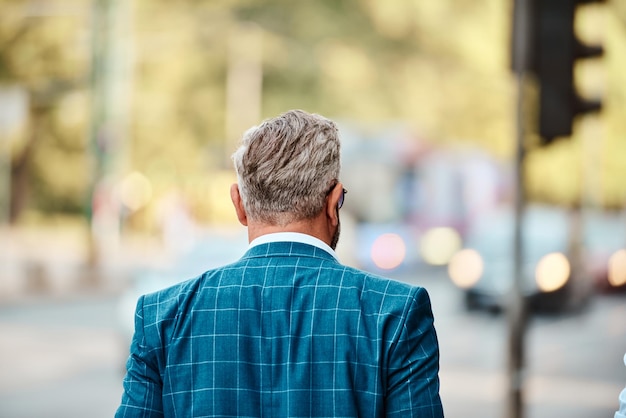 A senior businessman in a blue suit with a briefcase walking through the city.