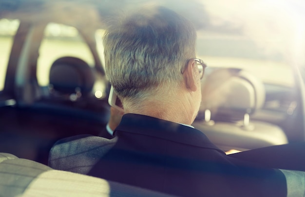 Photo senior businessman calling on smartphone in car