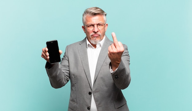 Senior businessman feeling angry, annoyed, rebellious and aggressive, flipping the middle finger, fighting back