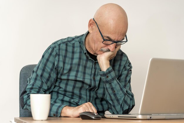 Senior businessman in front of laptop having a headache