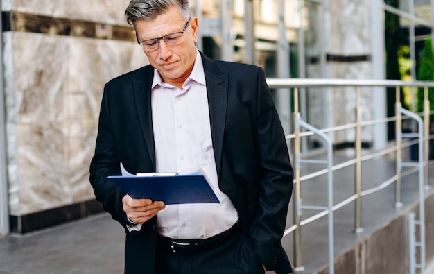 Senior businessman in glasses attentively  reading document 