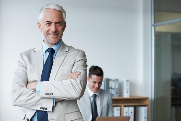 Foto senior uomo d'affari ritratto e fiducia o mentore agenzia e orgoglio per la formazione in ufficio persona maschile felice braccia incrociate e sorriso per il supporto in consulente di gestione e portatile per la pianificazione