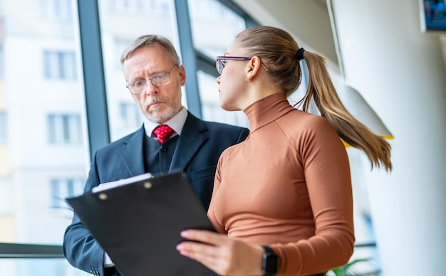 Senior businessman signs a contract with the assistance of a mature businesswoman.