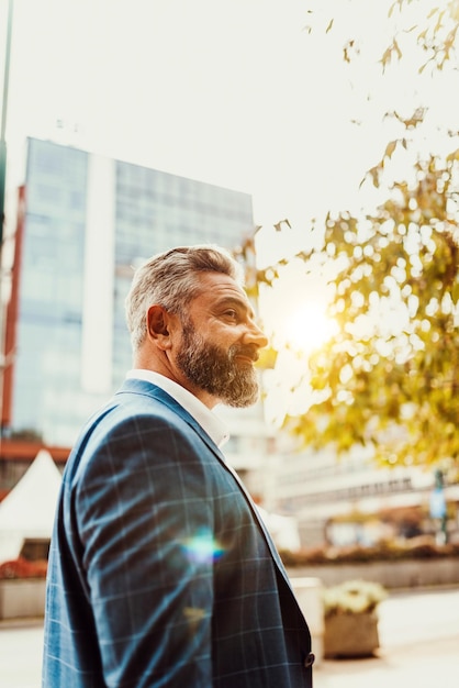 A senior businessman in a suit walking around the city after work