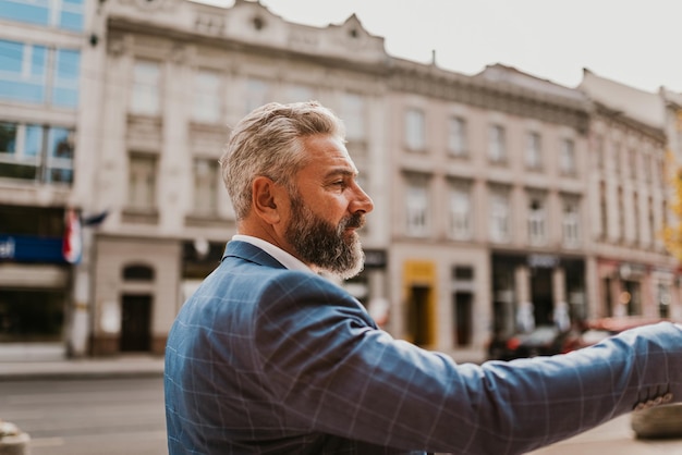 A senior businessman in a suit walking around the city after work