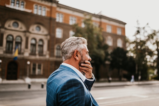 A senior businessman in a suit walking around the city after work