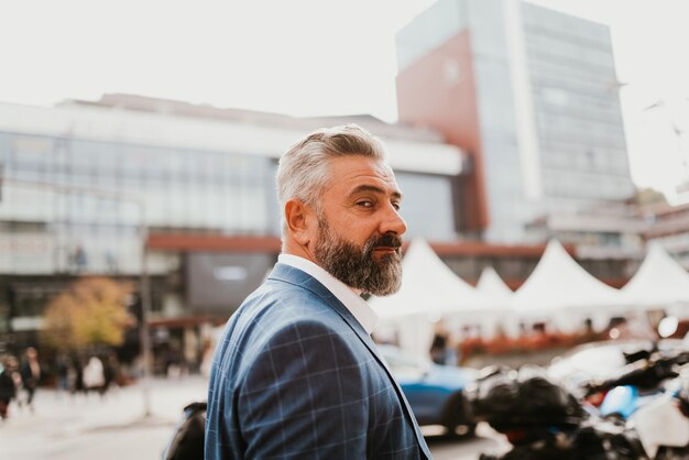 A senior businessman in a suit walking around the city after work.